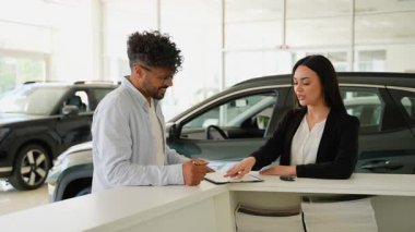 Araba satın alma işlemi, pazarlamacı kadının memnun müşterinin anahtarlarını sunması ve modern galeride başarılı bir otomotiv işlemini temsil etmesiyle sona eriyor.