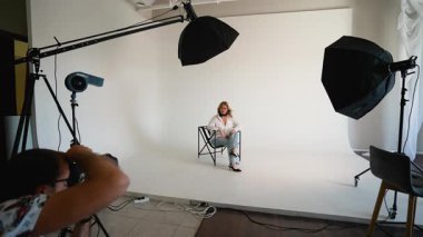 Profesyonel bir fotoğrafçının güzel bir kadın modelin fotoğraflarını çektiği sahne arkası görüntüsü.