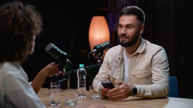 Canlı yayın sırasında canlı bir sunucuyla canlı bir konuşma yaparken akıllı telefonunu kullanan karizmatik erkek konuşmacı.