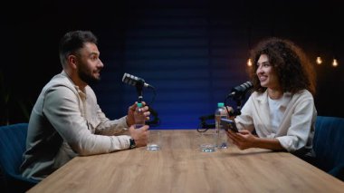 İki farklı radyo sunucusu, bir erkek ve bir kadın canlı yayında podcast yaparken ya da profesyonel bir stüdyoda mikrofonlar ve ses ekipmanlarıyla canlı yayında sohbet ediyorlar.