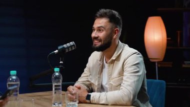 Modern bir stüdyoda canlı yayında profesyonel bir mikrofona konuşan yakışıklı bir erkek konuşmacı. Karizmatik içerik yaratıcısı bir podcast kaydederken görüşünü izleyicilerle paylaşıyor