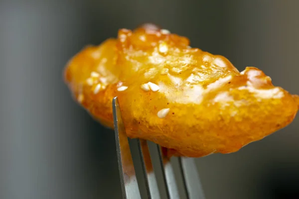 stock image Chicken meat dipped in an orange sauce crust with noodles as garnish