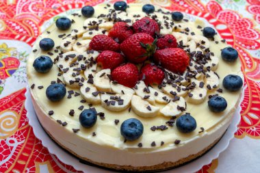 Beyaz çikolatalı, çilekli, yaban mersinli ve çikolatalı lezzetli bir cheesecake.