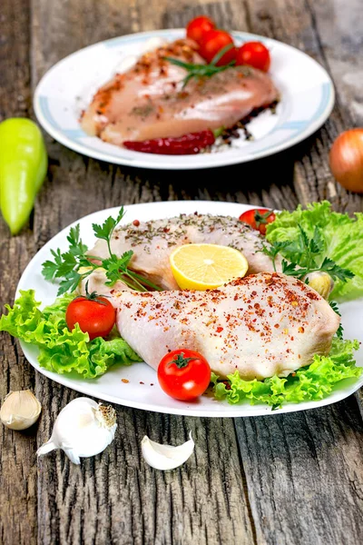 Raw chicken meat - raw chicken breast and raw chicken drumstick with spices on plate, on rustic table