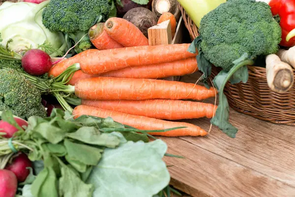 Fresh organic carrots and loads of veggies, healthy vegetarian food on table