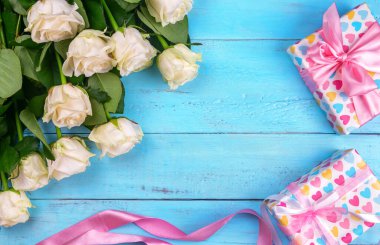 Mavi ahşap arka planda bir sürü beyaz gül, hediye, anneler gününe bir kartpostal, Sevgililer Günü ya da bir kadın günü. Tebrik kartı. metin için yer.