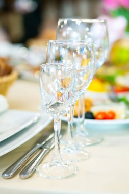 Güzel düzenlenmiş bir yemek masasında canlı tabakların yanında bir sıra parıldayan bardaklar, neşeli bir atmosfer yaratıyor..