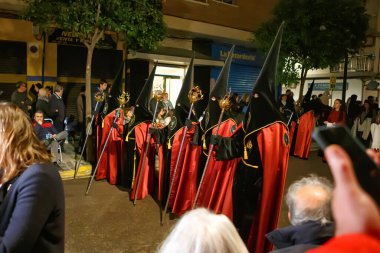 Akşamları, kalabalık bir caddede geleneksel kıyafet yürüyüşüne katılanlar etrafı izleyiciler ve atmosferik aydınlatmalarla çevrili..