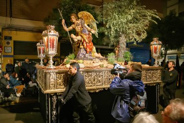 Akşamları, kalabalık bir caddede geleneksel kıyafet yürüyüşüne katılanlar etrafı izleyiciler ve atmosferik aydınlatmalarla çevrili..