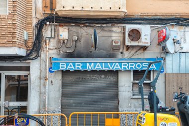 İspanya, Valencia, 29 Mart 2024: Panjurlu bar Malvarrosa, Valencia 'da sakin bir sokak ve kentsel unsurlarla çevrili mavi işaretini sergiliyor..