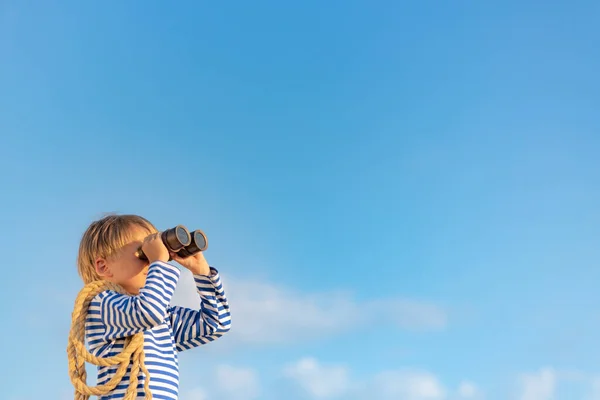 stock image Happy child looking through vintage binoculars against blue sky. Kid having fun in summer. Imagination and freedom concept.