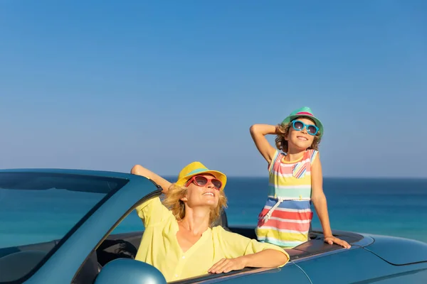 海で車で幸せな家族旅行 青いキャブリオレットでお母さんと子供が楽しんでいます 夏休みのコンセプト — ストック写真