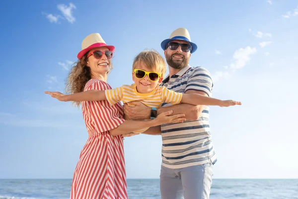 幸せな家族はビーチで楽しんでいます 青い海と空を背景に息子を持つ母と父 夏休みのコンセプト — ストック写真