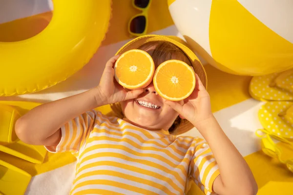 幸せな子供のサングラスのようなオレンジの果物のスライスを保持 子供の縞模様のTシャツビーチタオルの上に横たわるを着て 健康的な食事と夏休みのコンセプト — ストック写真