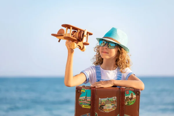 暑假带着老式手提箱的孩子 女孩在海滩上玩木制飞机 小孩坐在大海和天空的背景下 旅行和探险概念 — 图库照片