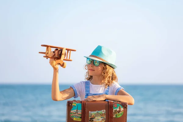 暑假带着老式手提箱的孩子 女孩在海滩上玩木制飞机 小孩坐在大海和天空的背景下 旅行和探险概念 — 图库照片