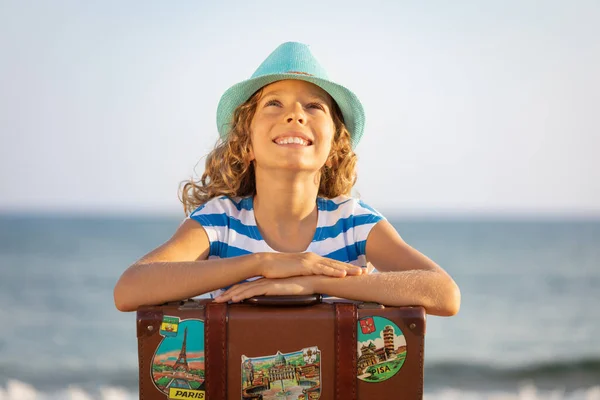 夏休みにヴィンテージのスーツケースを着た子供 ビーチで遊んでいる女の子 子供は海と空の背景に座っている 旅と冒険のコンセプト — ストック写真