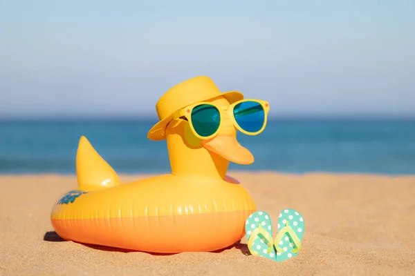青い海と空の背景に対して砂の上にビーチフリップフロップと黄色のアヒル 夏休みのコンセプト — ストック写真