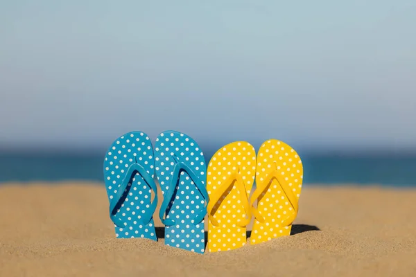 海と空の背景に対して砂のビーチで多色のフリップフロップ 夏休みと旅行のコンセプト — ストック写真