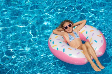 Açık havuzda yüzen mutlu çocuk. Kız yaz tatilinde eğleniyor. Sağlıklı yaşam tarzı kavramı