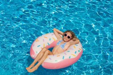Açık havuzda yüzen mutlu çocuk. Kız yaz tatilinde eğleniyor. Sağlıklı yaşam tarzı kavramı