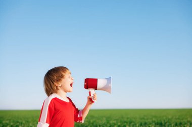 Mutlu çocuk futbolcu gibi davranıyor. Dışarıdaki çocuğun portresi. Çocuk yeşil alana karşı hoparlör açıyor. Başarı ve kazanan konsepti