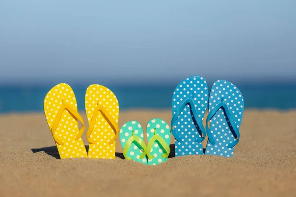 海と空の背景に対して砂のビーチで多色のフリップフロップ 夏休みと旅行のコンセプト — ストック写真