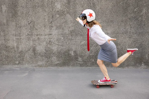 Happy businesswoman riding skateboard. Outdoor portrait of young woman. Back to work, start up and business idea concept