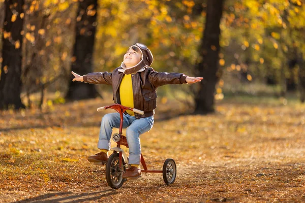 黄色の葉の背景に幸せな子供のパイロットの肖像画 秋の公園で自転車で屋外に乗る面白い子供 自由と想像力の概念 — ストック写真