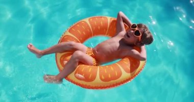 Happy child having fun on summer vacation. Kid playing in swimming pool. Active healthy lifestyle concept. Slow motion