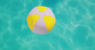 Yellow beach ball floating in swimming pool. Summer vacation concept