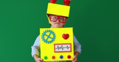 Happy child wearing toy robot. Funny kid playing at home. Success, creative and innovation technology concept. Slow motion