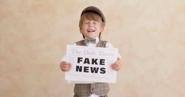 コンクリートの壁の背景に向かって叫んでいる新聞少年 偽のニュースを売ってる ヴィンテージの衣装を着た子供 子供が新聞を持ってる スローモーション — ストック動画