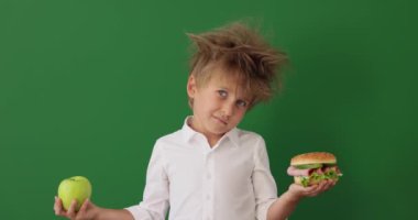 Surprised child in class. Funny kid against green chalkboard background. Back to school and education concept. Slow motion