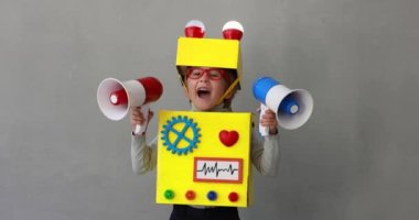 Happy child wearing toy robot. Funny kid shouting through loudspeaker. Success, creative and innovation technology concept. Slow motion