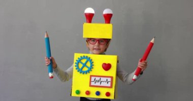 Happy child wearing toy robot. Funny kid holding pencils. Success, creative and innovation technology concept. Slow motion