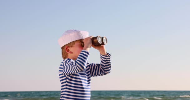 幸せな子供は船員のふりをする ビーチで遊んでいる子供 スパイガラスを通して見ている男の子 夏休みと旅行のコンセプト スローモーション — ストック動画