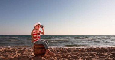Happy child pretend to be sailor. Kid having fun at beach. Boy looking through spyglass. Summer vacation and travel concept. Slow motion
