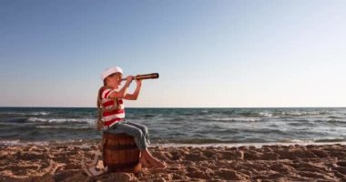 Happy child pretend to be sailor. Kid having fun at beach. Boy looking through spyglass. Summer vacation and travel concept. Slow motion