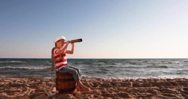 Happy child pretend to be sailor. Kid having fun at beach. Boy looking through spyglass. Summer vacation and travel concept. Slow motion