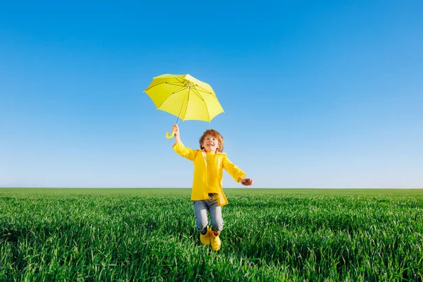春の緑のフィールドで屋外で遊んで幸せな子供 笑顔子供とともに黄色傘反青夏空の背景 — ストック写真