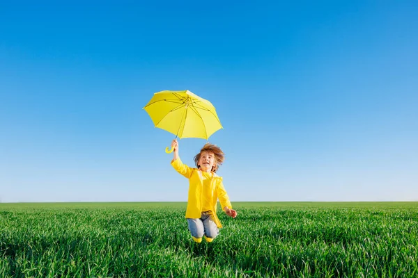 春の緑のフィールドで屋外で遊んで幸せな子供 笑顔子供とともに黄色傘反青夏空の背景 — ストック写真