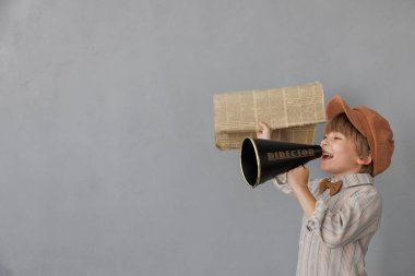 Newsboy shouting through loudspeaker against grunge wall background. Kid selling newspaper. Child wearing vintage costume. Social media and Internet nerwork concept clipart