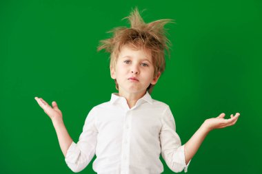 Sınıftaki şaşkın çocuk. Yeşil karatahta arka planına karşı komik çocuk. Okula ve eğitim konseptine dönüş