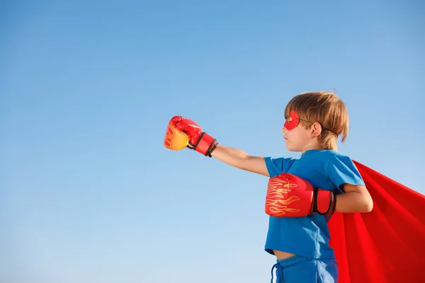 夏の青空に対するスーパーヒーローの子供 スーパーヒーローの少年は楽しいアウトドアを持っています 健康的なライフスタイルのコンセプト — ストック写真