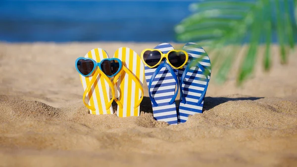 青い海の背景に対して黄色の砂の上にフリップフロップとサングラス 夏休みと旅行のコンセプト — ストック写真