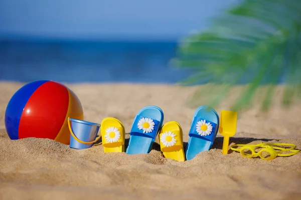 青い海の背景に対して黄色の砂の上の子供たちのフリップフロップ ビーチボール シュノーケリング 夏休みのコンセプト — ストック写真