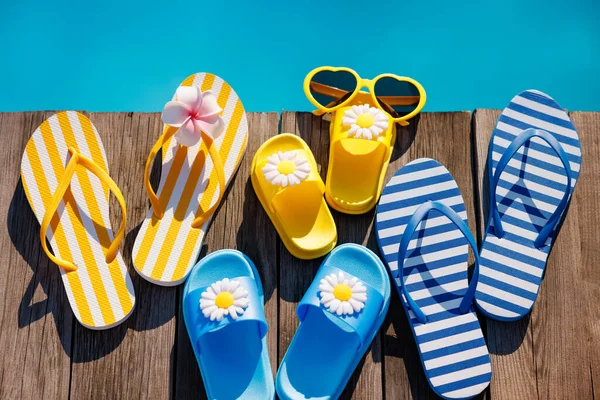 木製の背景にビーチフリップフロップとサングラス スイミングプールの青い水に対する休暇のためのもの 夏休みと旅行のコンセプト ロイヤリティフリーのストック画像