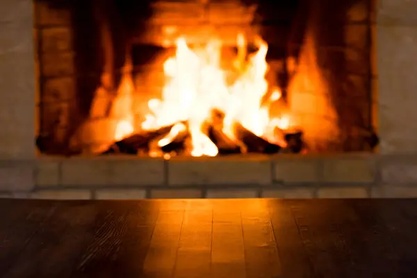 暖炉で木を燃やすことに対する空の古い木のテーブル 冬休みクリスマスと新年のコンセプト ストック写真