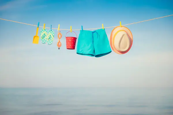 海滩帽 翻领和护目镜挂在晾衣绳上 在蓝天和大海下度假的东西 暑假和旅行概念 图库图片